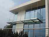 Hängande balkong med stålkonstruktion. Glasgolv och stolpfritt glasräcke med överliggare i rostfritt stål.