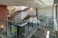 Hängande mezzanine med stålkonstruktion. Glasgolv och stolpfritt glasräcke med överliggare i rostfritt stål