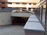 Uppfart till den underjordiska parkeringen med tak av polykarbonatpaneler på stålkonstruktioner och glasräcke med rostfria stolpar och handledare
