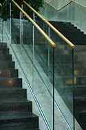 Stolpfritt glasräcke med överliggare i trä monterad på trappor. Golvmonterad med hjälp av stålskena