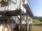 Utvändig trappa og balkong med stålstödstrukturer, träplankor och glasräcken