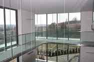 Hängande mezzanine med stålkonstruktion. Glasgolv och stolpfritt glasräcke med överliggare i rostfritt stål